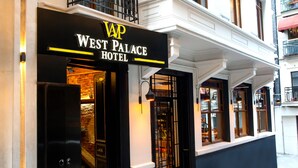 The exterior of the West Palace Hotel with a black facade, a signboard, and a staircase leading to the entrance. - West Palace Hotel (Istanbul)