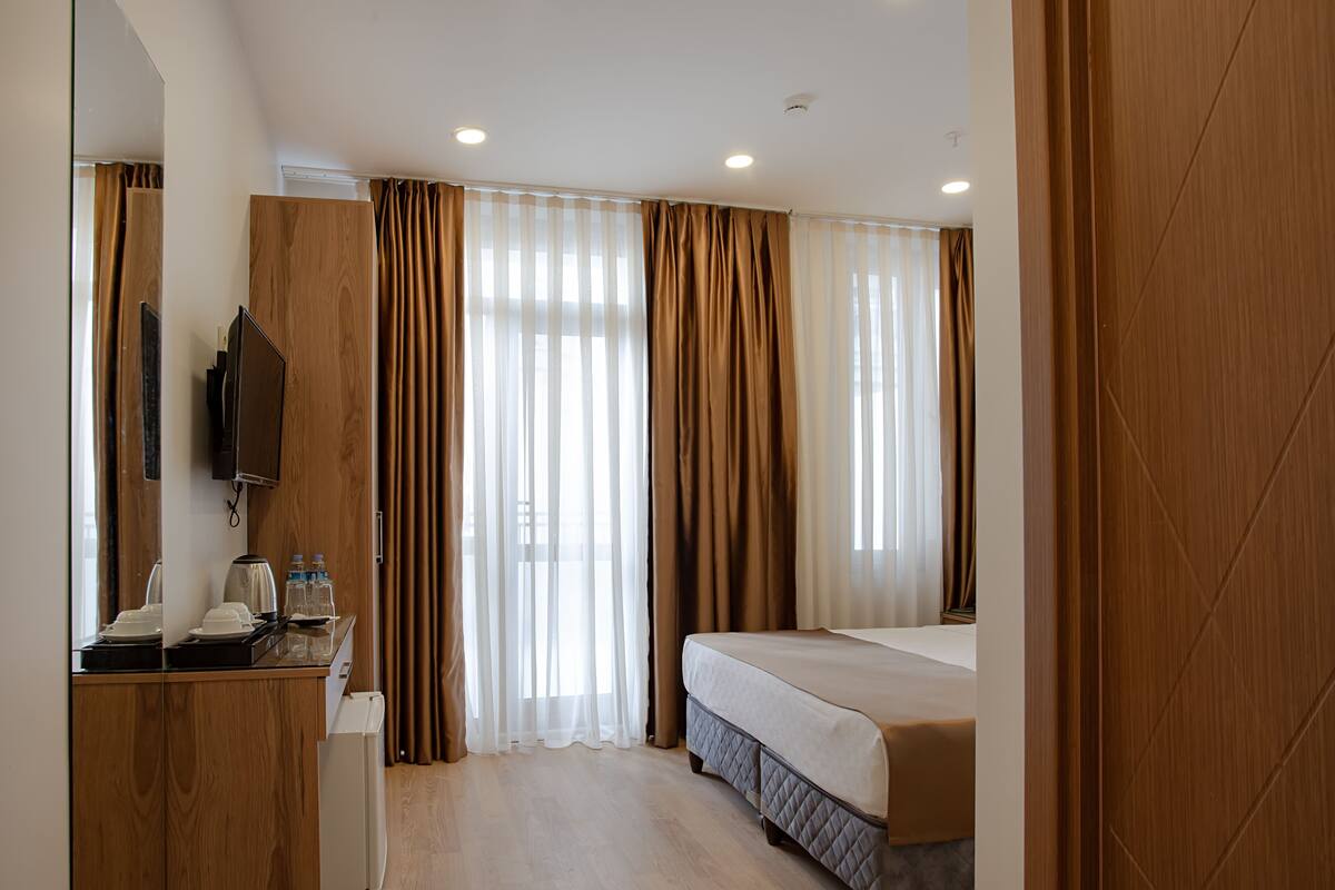 A hotel room with a bed, a desk with a coffee maker, and a television.