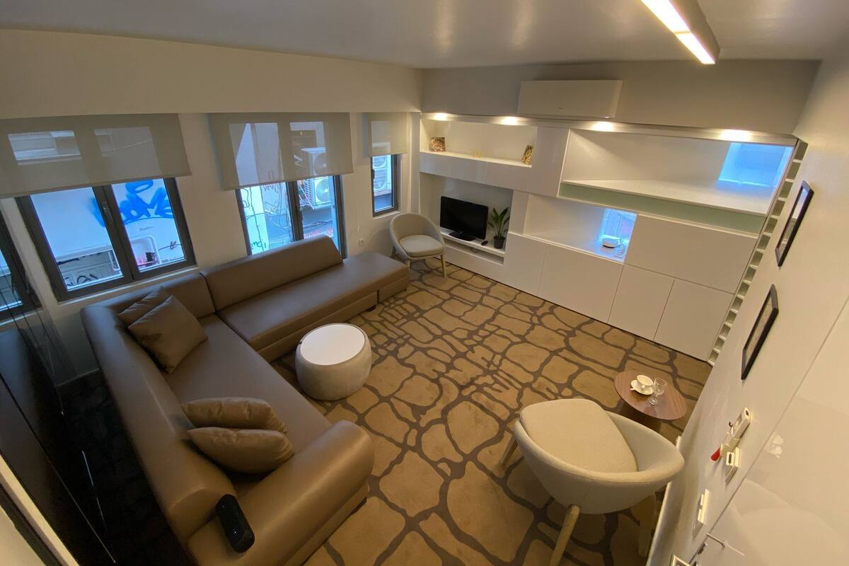 A modern living room with a sofa, a small round table, a TV, and a fireplace.