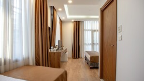 A hotel room with two beds, a desk with a chair, a wardrobe, and a bathroom. - West Palace Hotel (Istanbul)