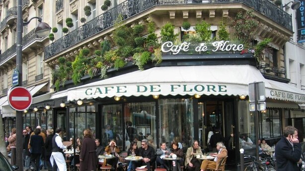 Un café appelé Café de Flore, doté d’une terrasse et d’une enseigne au-dessus de l’entrée.