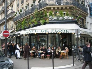 Un café llamado Cafe de Flore con mesas al aire libre y un letrero sobre la entrada.