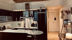 Une cuisine moderne avec des meubles noirs, des appareils en acier inoxydable et un îlot central en verre.