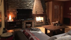 A cozy living room with a stone fireplace, a flat-screen TV, and a comfortable seating area with a sofa and a coffee table. - Charming house in a quiet and rural environment HUT3 005/004 (Llorts)