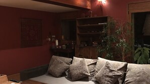 A cozy living room with a wooden coffee table, a sofa with patterned cushions, a wooden bookshelf, and a staircase with a railing. - Charming house in a quiet and rural environment HUT3 005/004 (Llorts)