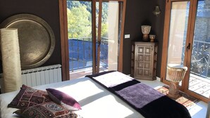 A bedroom with a large bed, a radiator, a wooden cabinet, and a window with a view of trees. - Charming house in a quiet and rural environment HUT3 005/004 (Llorts)