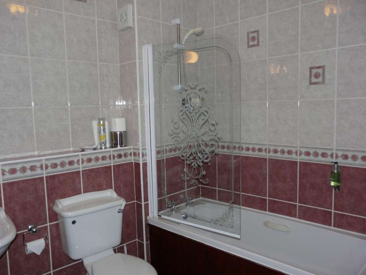 A bathroom with a toilet, a bathtub, and a shower enclosure.