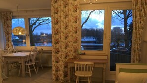 A dining area with a table and chairs, a small desk with a chair, and a sofa. - Gästeträume (Bremen)