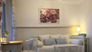 A cozy room with a bed, a desk with a lamp, a chair, and a wall-mounted picture. - Gästeträume (Bremen)