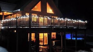 A wooden cabin with a balcony and a lit interior.