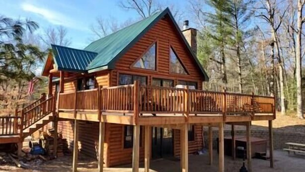 A wooden cabin with a balcony and a covered deck area.
