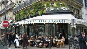Un caffè chiamato Cafe de Flore con posti a sedere all'aperto e un'insegna sopra l'ingresso.
