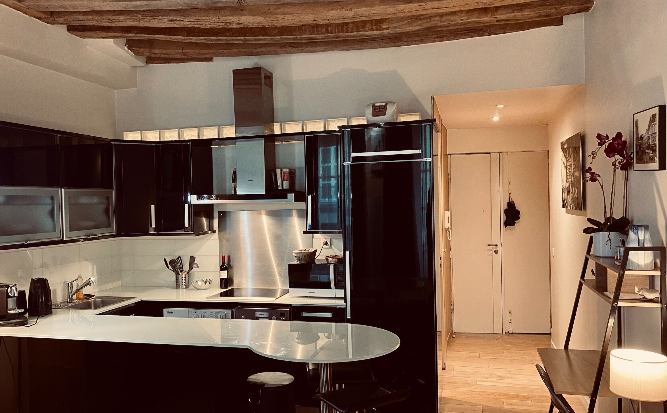 Una cucina moderna con pensili neri, elettrodomestici in acciaio inossidabile e un'isola in vetro.