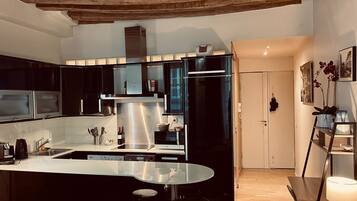 Una cucina moderna con pensili neri, elettrodomestici in acciaio inossidabile e un'isola in vetro.
