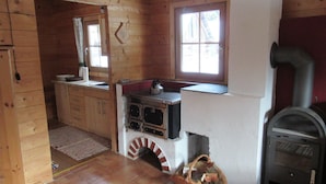 A wooden cabin interior with a kitchen area, a fireplace, and a window. - Preberhütte in Prebertal lies at 1500 meters above sea level (Tamsweg)