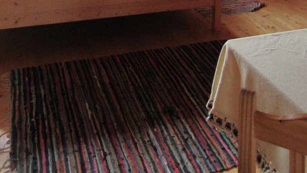 A cozy attic bedroom with a large bed, a small table, and a window with curtains. - Preberhütte in Prebertal lies at 1500 meters above sea level (Tamsweg)