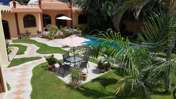 A courtyard with a pool, outdoor seating, and potted plants.