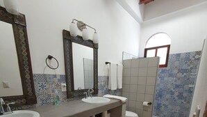 A bathroom with two sinks, a toilet, and a shower area.
