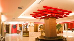A hotel lobby with a central reception desk, a decorative red ceiling structure, and a traditional Asian architectural element. - GreenTree Eastern Handan Daming County Bus Station (Handan)