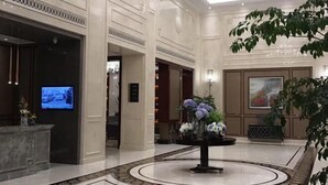 Un hall d’entrée spacieux avec un comptoir de réception, un téléviseur et un grand arrangement floral au centre.