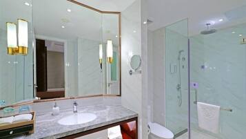 A modern bathroom with a marble sink, a large mirror, and a glass-enclosed shower.