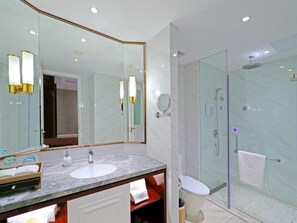A modern bathroom with a marble sink, a large mirror, and a glass-enclosed shower.