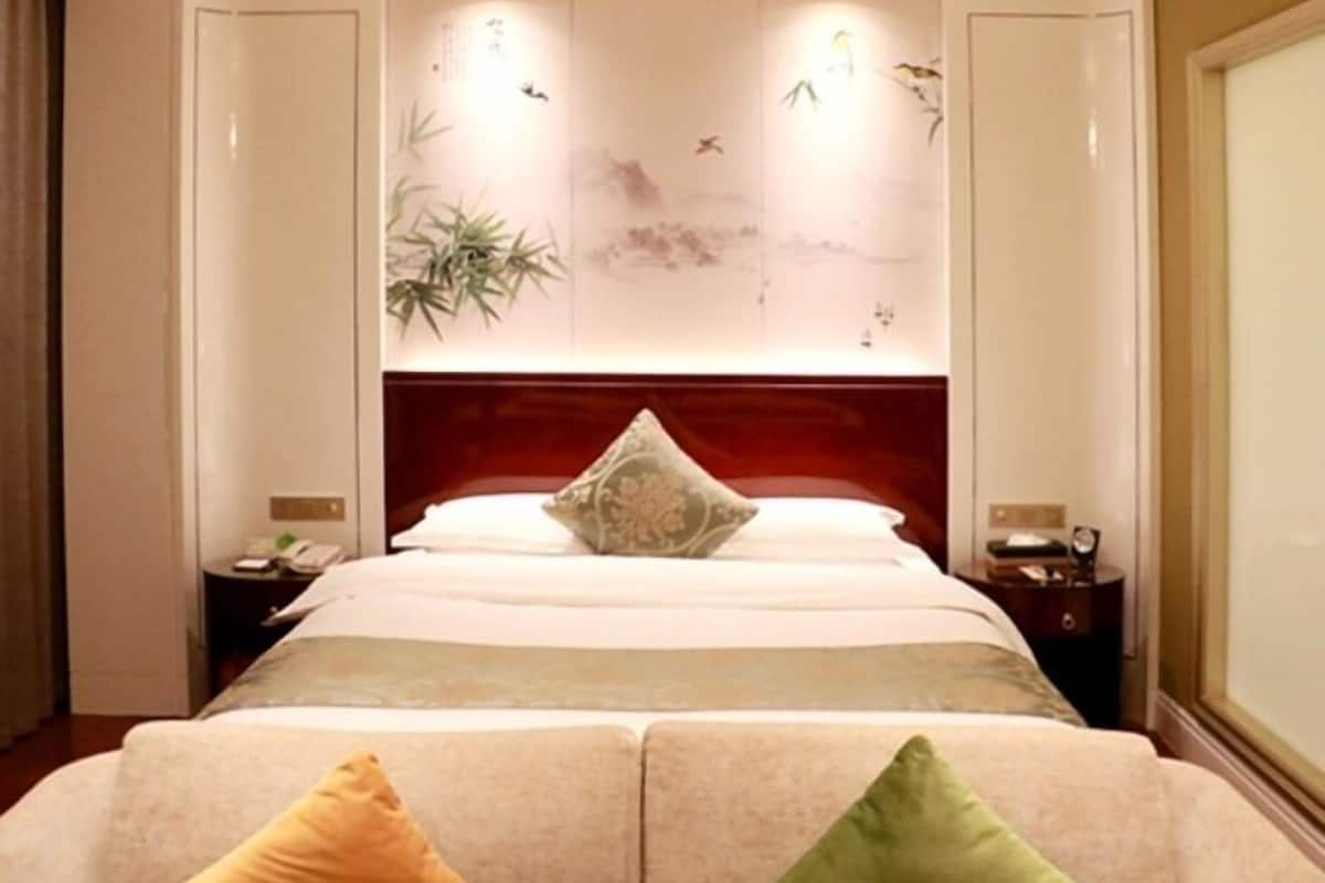 Ein Hotelzimmer mit einem großen Bett, einem hölzernen Kopfteil und einer Wand mit Kunstwerken.