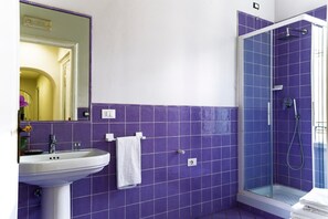 A bathroom with purple tiles, a white sink, and a glass-enclosed shower. - Live Florence Guesthouse (Florence)
