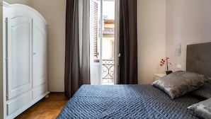 A bedroom with a bed, a wardrobe, and a balcony with a view. - Live Florence Guesthouse (Florence)