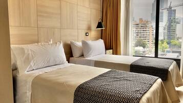 A hotel room with two beds, a large window with a city view, and a modern design.