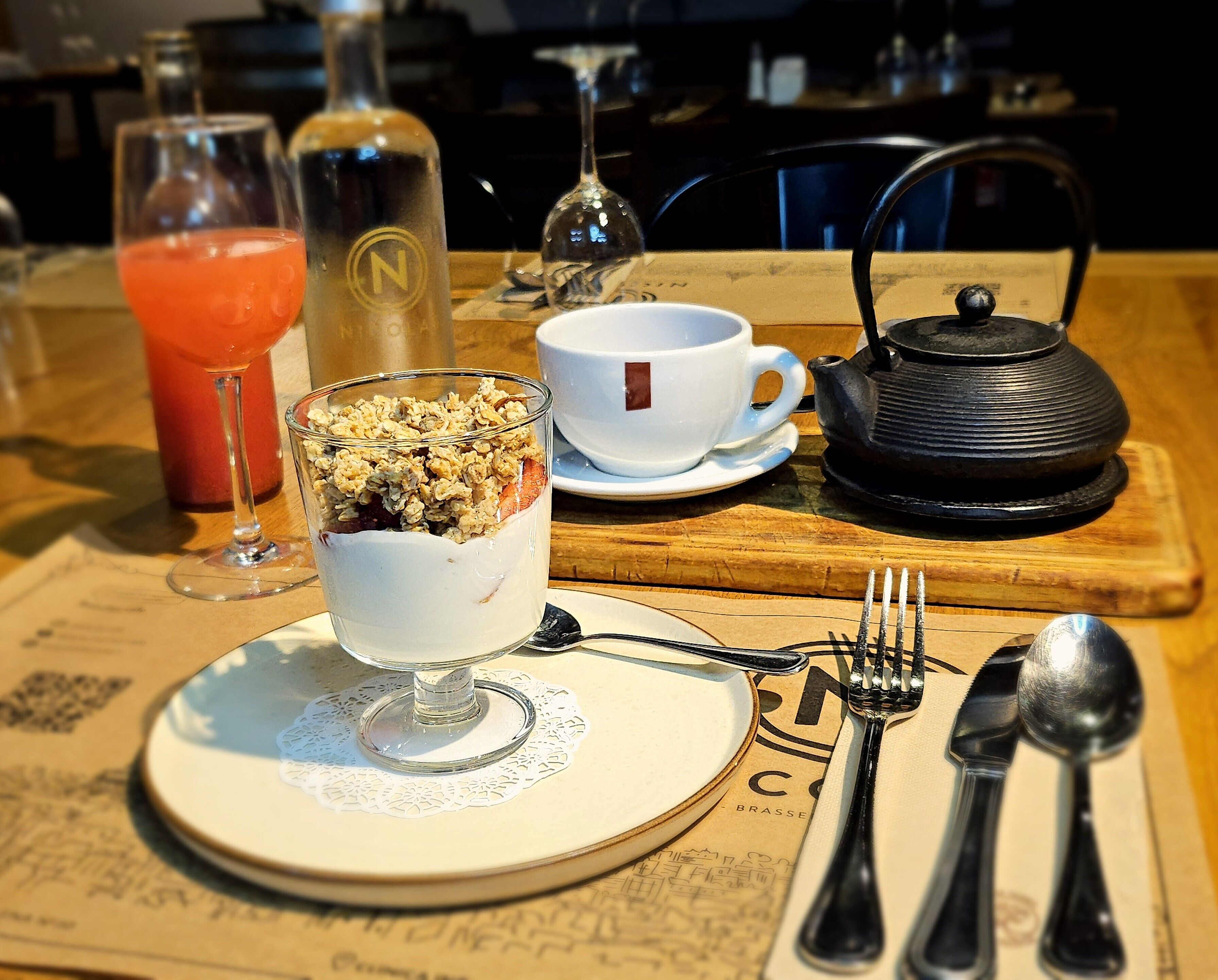 Een tafel met een dessert, een theepot en een kop koffie.