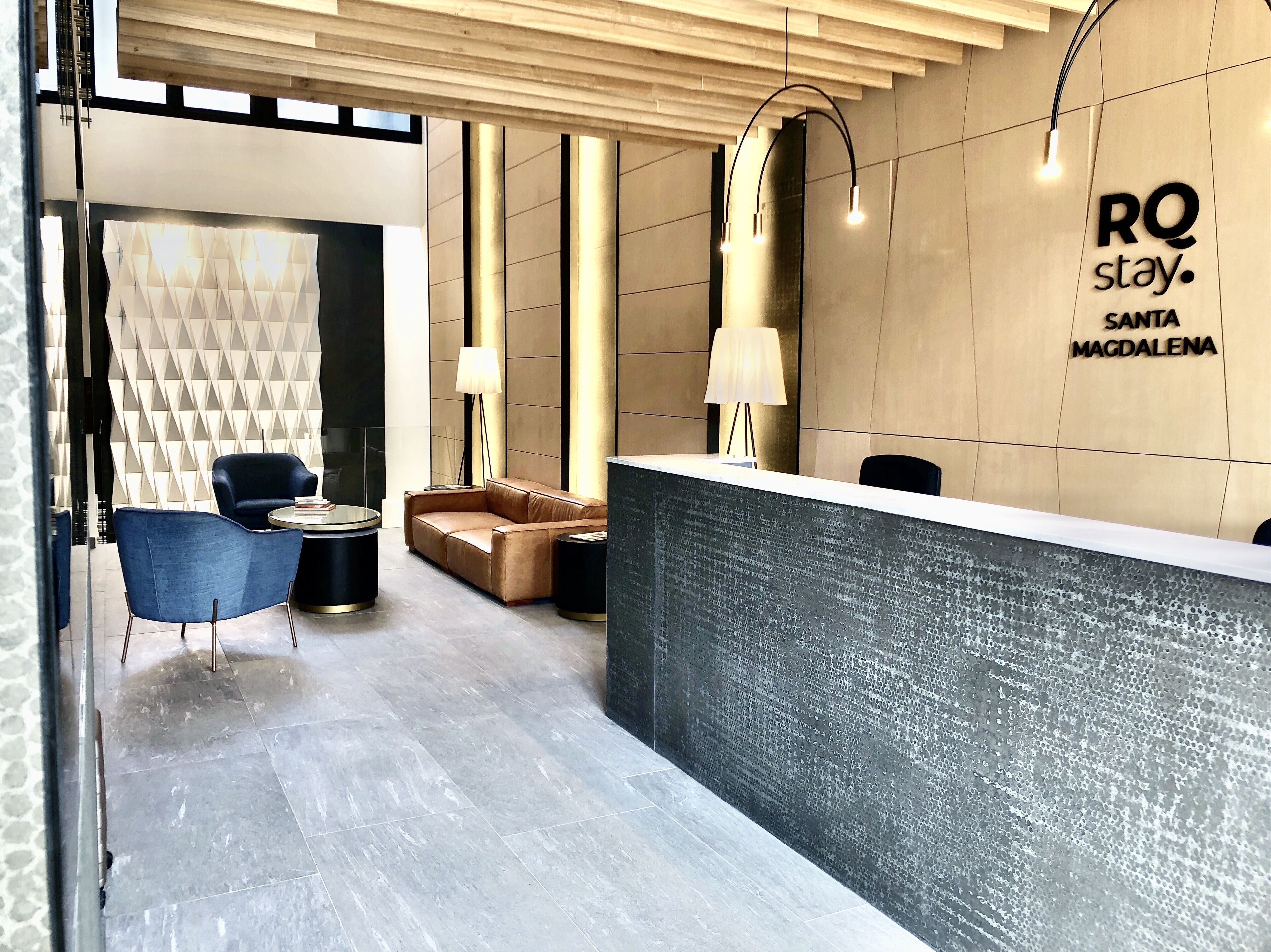 Un área de recepción moderna con un mostrador, un sofá, una silla y una lámpara.