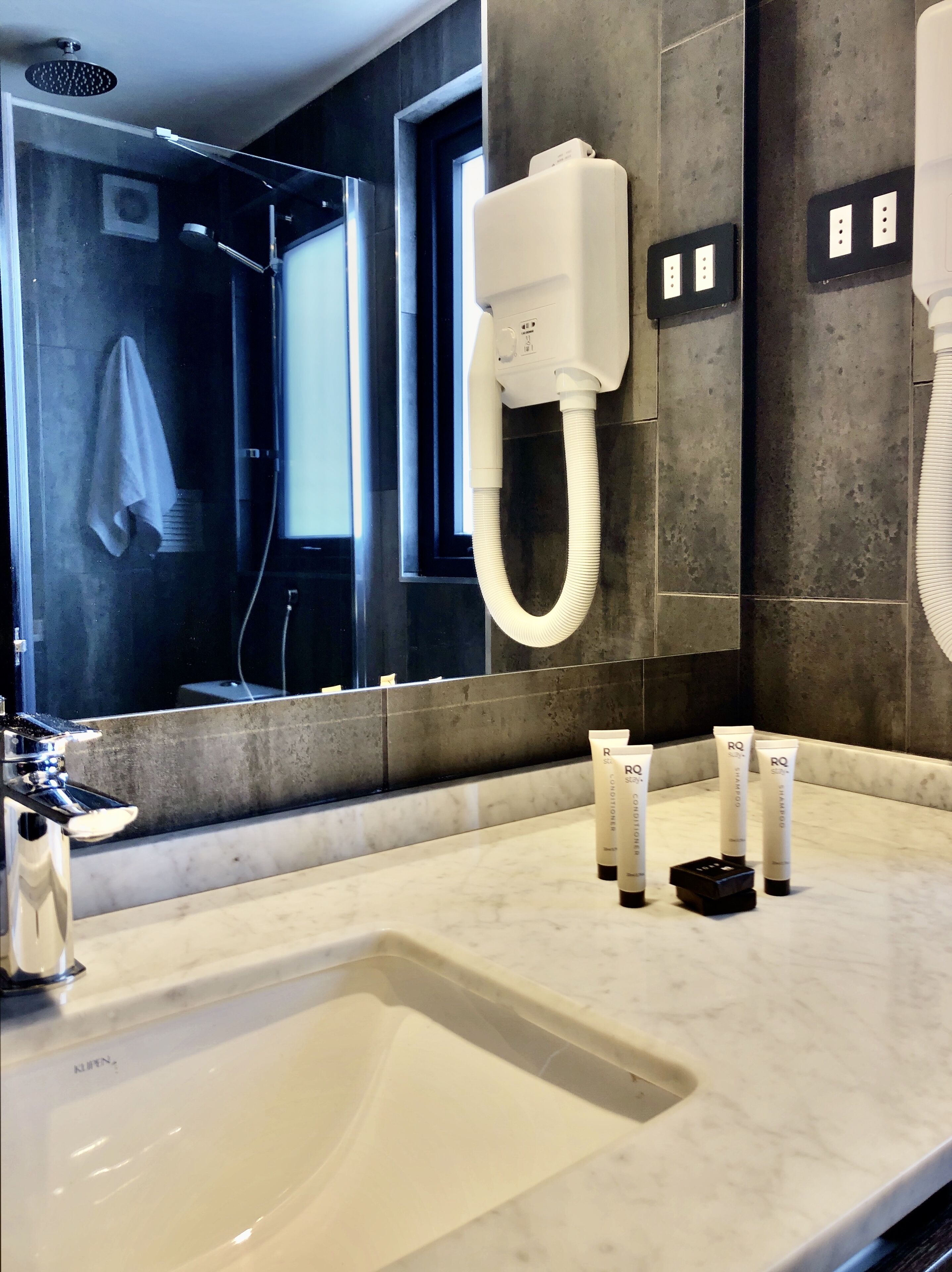 Ein modernes Badezimmer mit einem großen Spiegel, einem Waschbecken und einer Duschbrause.