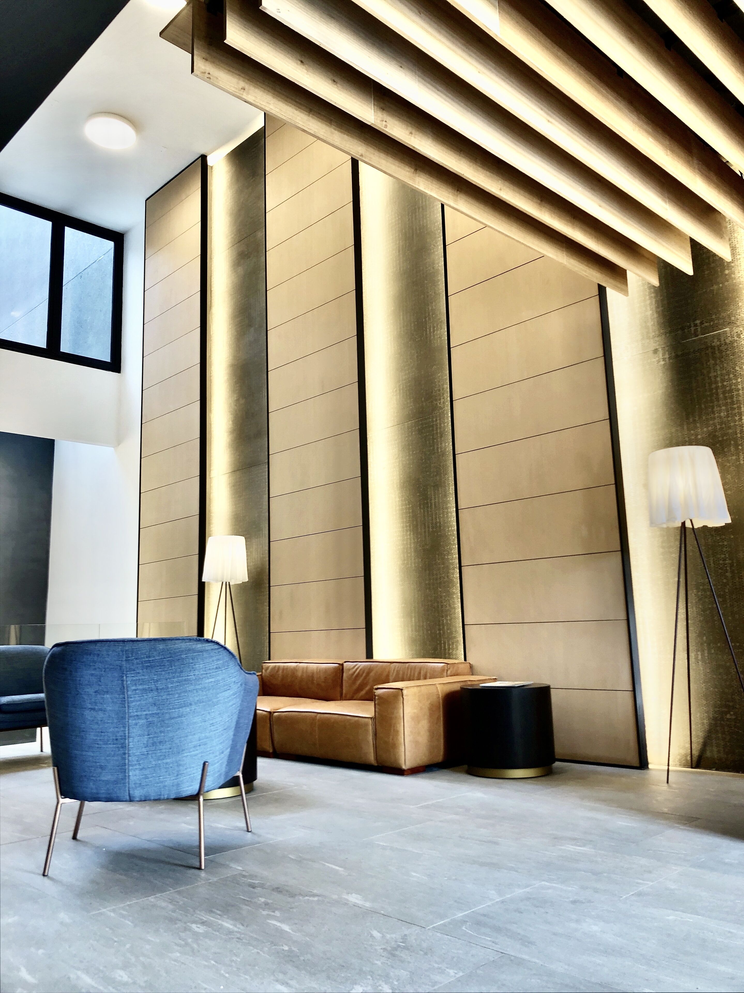 A modern interior with a sectional sofa, a blue armchair, and a floor lamp.