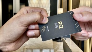A person holding a black card with 'RO' and a website URL. - RQ Santa Magdalena (Santiago)