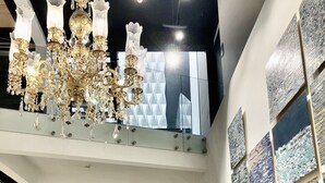 A modern interior with a grand chandelier, geometric wall art, and a staircase. - RQ Santa Magdalena (Santiago)