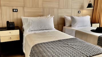 Habitación de hotel con dos camas, una mesita de noche con teléfono y una lámpara.