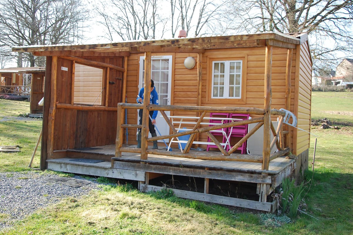 A wooden cabin with a porch, a door, and a window.