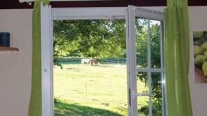A window with a view of a grassy field and trees. - Camping La Chevauchée (Bussière-Dunoise)