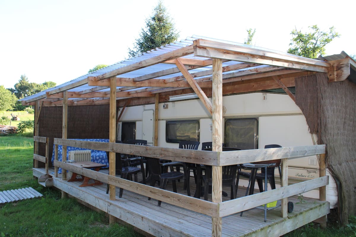 A covered outdoor area with a wooden deck, chairs, and a table.