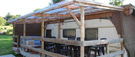 A covered outdoor area with a wooden deck, chairs, and a table.