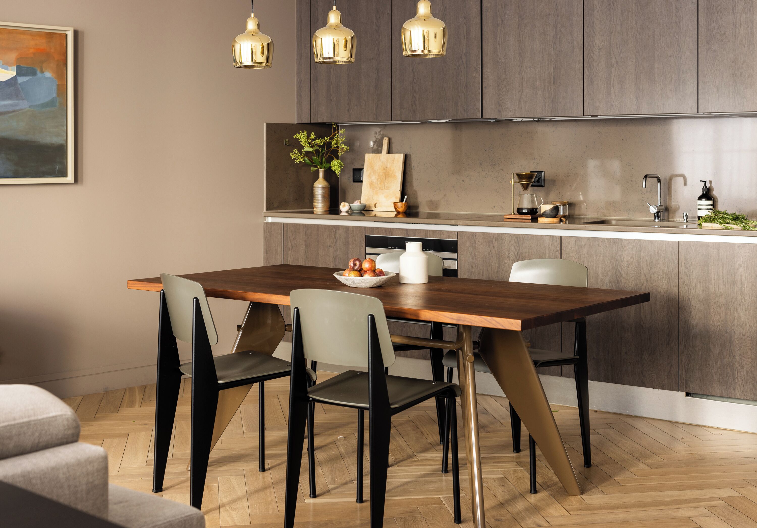 Una cocina moderna con una mesa de comedor de madera, dos sillas e iluminación colgante.