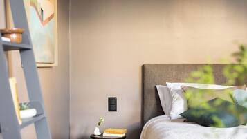 Un dormitorio moderno con cama, mesita de noche, escalera y un cuadro en la pared.