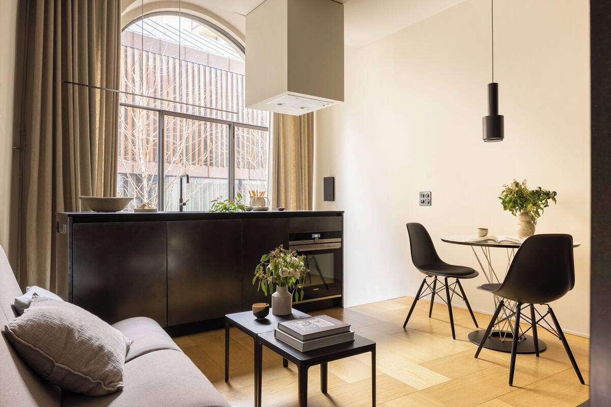 A modern living room with a sofa, a coffee table, and a dining area with chairs and a table.