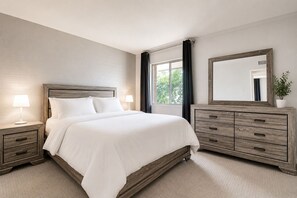 A bedroom with a bed, bedside tables, a dresser, a mirror, and a window with curtains.