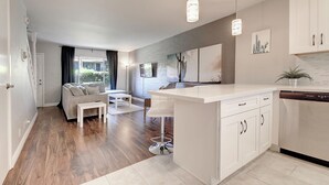 Une cuisine moderne avec des meubles blancs, un îlot central et des luminaires suspendus.