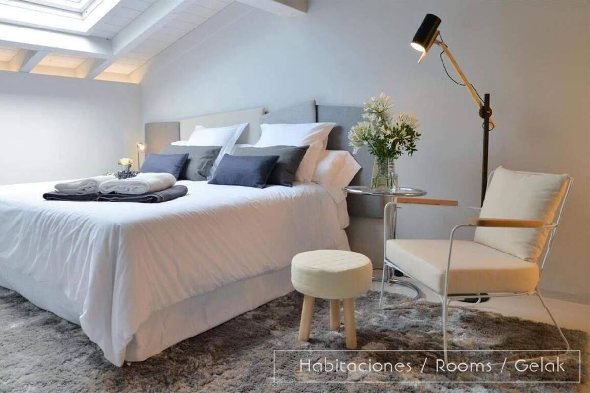 A bedroom with a bed, bedside table, lamp, chair, and a skylight.