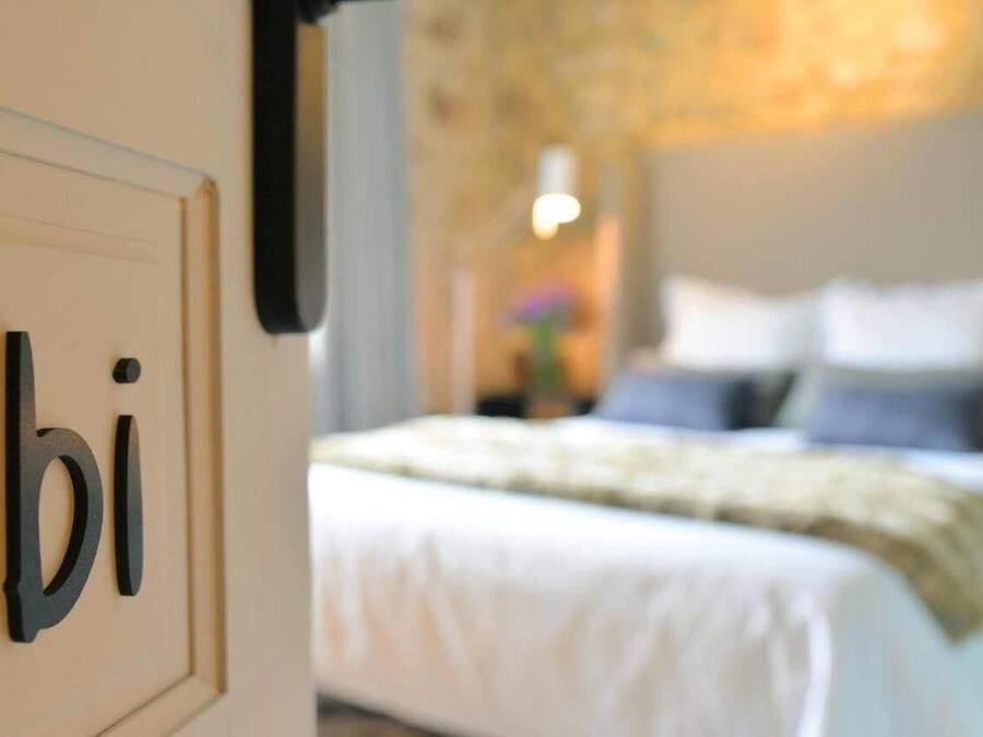 Un dormitorio con cama, almohadas y una mesita de noche.