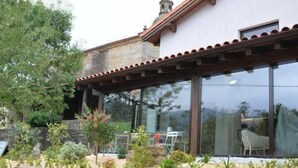A house with a tiled roof, large windows, and a garden with steps leading to a wooden deck. - Hotel Garaiko Landetxea (Garai)
