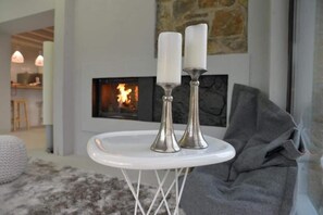 A white table with two silver candle holders and white candles in a modern living room with a fireplace. - Hotel Garaiko Landetxea (Garai)